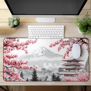 May include: A white and pink mouse pad with a Japanese mountain scene, cherry blossoms, and a pagoda. The mouse pad is designed to look like a traditional Japanese landscape.
