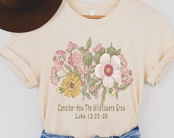 Puede incluir: Una camiseta beige con un diseño floral y el texto "Consider: How The Wildflowers Grow Luke 12:25-28".