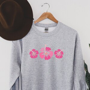 May include: A gray sweatshirt with a pink hibiscus flower design on the front.