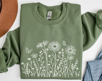 May include: A green sweatshirt with a white outline of a field of flowers and butterflies.