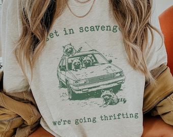 Może przedstawiać: Szara bluza z nadrukiem z szopami w samochodzie i tekstem "Get in scavengers we're going thrifting".
