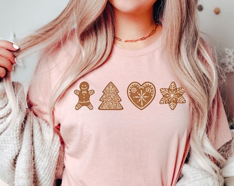 May include: A pink t-shirt with a gingerbread man, a gingerbread tree, a gingerbread heart, and a gingerbread snowflake design.