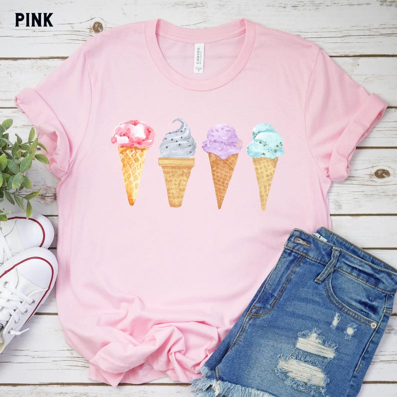 May include: Pink t-shirt with a graphic of four ice cream cones in a row. The ice cream cones are in different colors and flavors, including pink, black, purple, and blue.