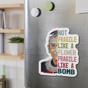 May include: A colorful portrait of Ruth Bader Ginsburg with the text "Not Fragile Like A Flower Fragile Like A Bomb" in a vintage style font.