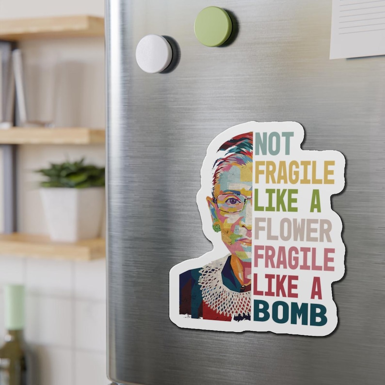 May include: A colorful portrait of Ruth Bader Ginsburg with the text "Not Fragile Like A Flower Fragile Like A Bomb" in a vintage style font.