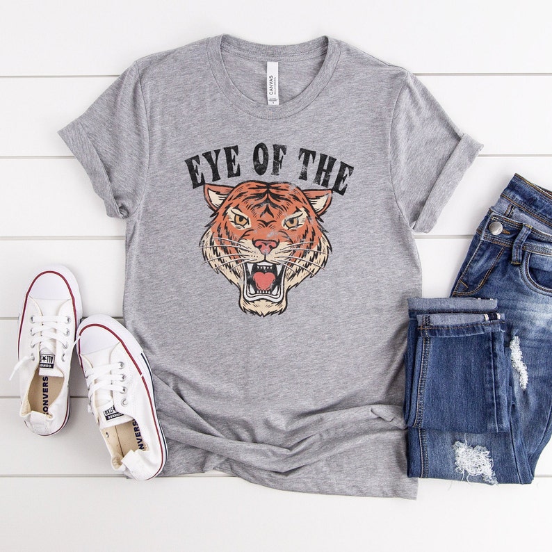 May include: Gray t-shirt with a vintage-style tiger graphic and the text "Eye of the Tiger".