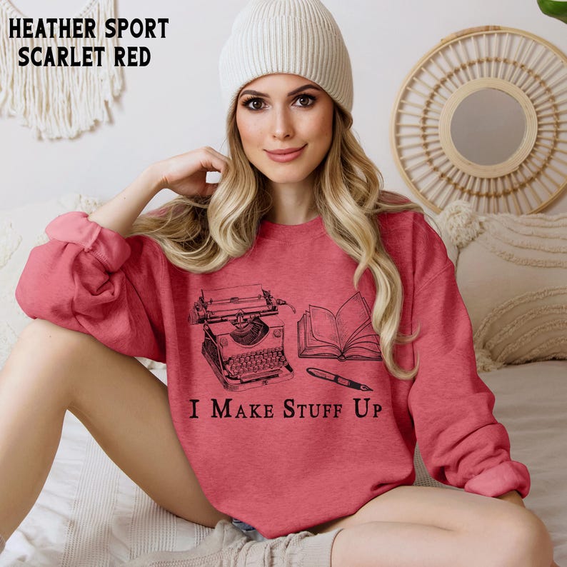Puede incluir: Sudadera roja escarlata con un gr&aacute;fico negro de una m&aacute;quina de escribir, un libro abierto y un bol&iacute;grafo. El texto "I MAKE STUFF UP" est&aacute; impreso debajo. La sudadera es de material deportivo jaspeado.