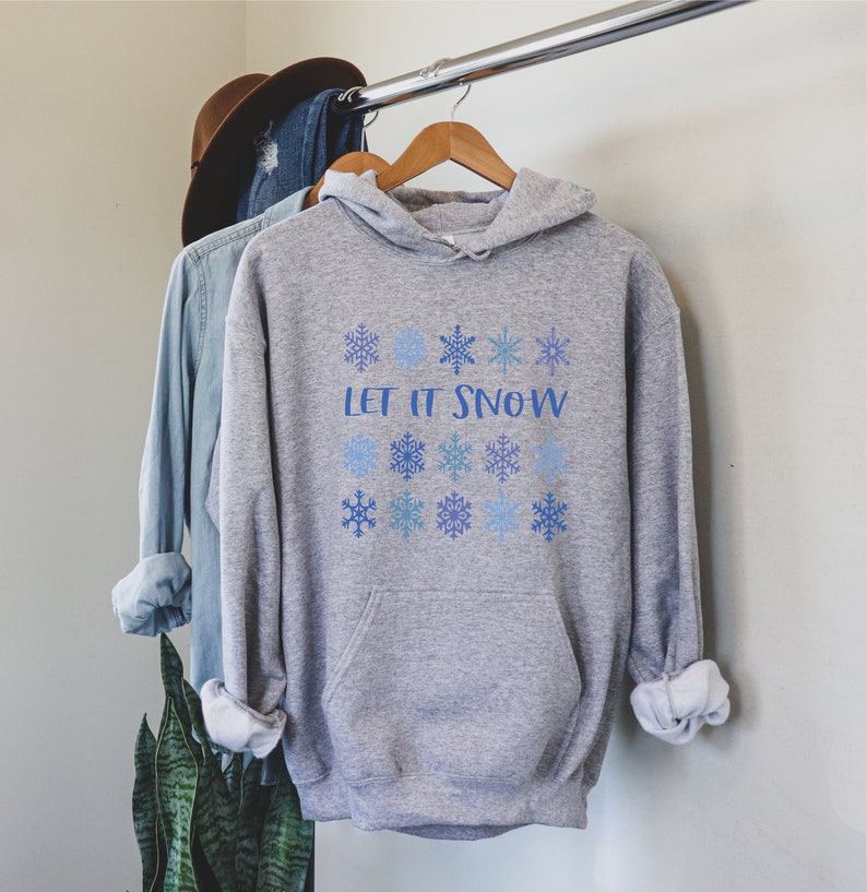 May include: A gray hooded sweatshirt with the text "Let it Snow" printed in blue. The sweatshirt is decorated with blue snowflakes.