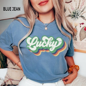 May include: A blue jean t-shirt with a retro-style graphic that says "Lucky" in rainbow colors.