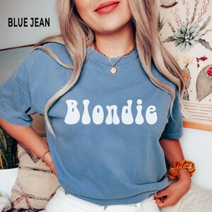 以下が含まれることがあります： レトロなフォントで「Blondie」という文字が白でプリントされた、ブルーのジーンズのTシャツです。