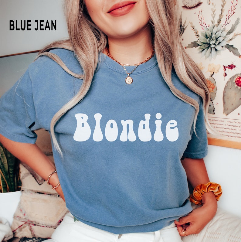 以下が含まれることがあります： レトロなフォントで「Blondie」という文字が白でプリントされた、ブルーのジーンズのTシャツです。