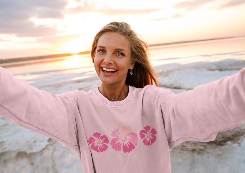 May include: A pink sweatshirt with a row of three pink hibiscus flowers printed on the front.