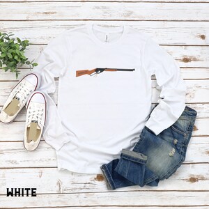 May include: White long-sleeve t-shirt with a brown and black toy rifle printed on the front.