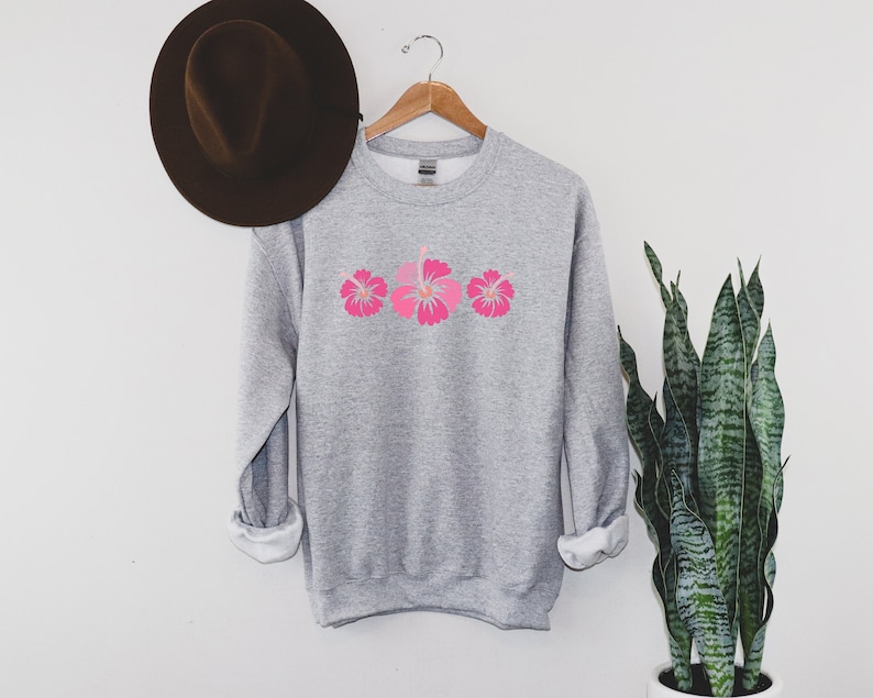 May include: A gray sweatshirt with a pink hibiscus flower design on the front.