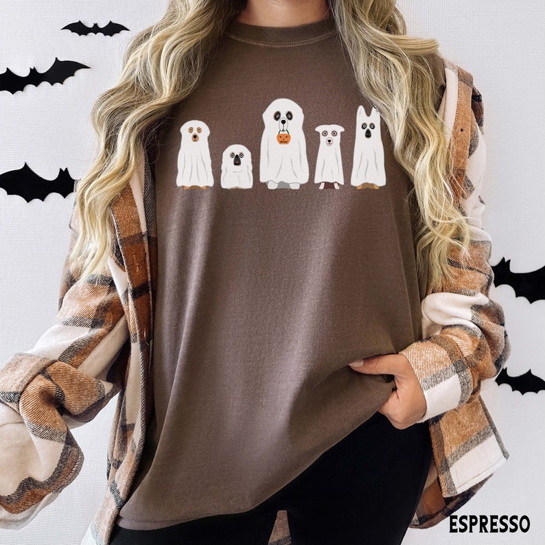 May include: A brown t-shirt with a graphic of five dogs dressed as ghosts for Halloween. The dogs are all different breeds and sizes. The ghosts are white with black eyes and mouths. The shirt is a relaxed fit and has a crew neck.