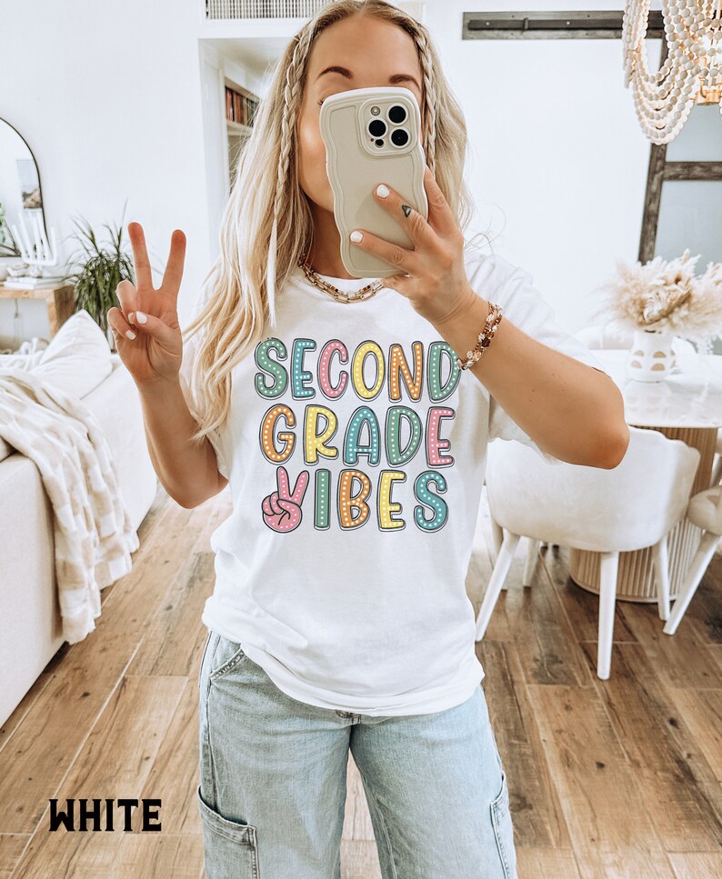 May include: White t-shirt with the text "Second Grade Vibes" in colorful letters with a peace sign graphic.