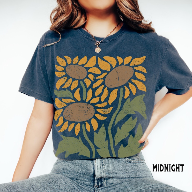 May include: A navy blue t-shirt with a graphic print of three stylized sunflowers in shades of yellow, brown, and green.