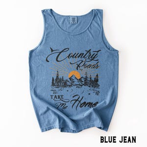 K&ouml;nnte beinhalten: Hellblaues Tanktop mit dem Text "Country Roads Take Me Home". Das Design zeigt eine Berglandschaft mit Sonne und B&auml;umen. Das Tanktop hat die Farbe Blue Jean.