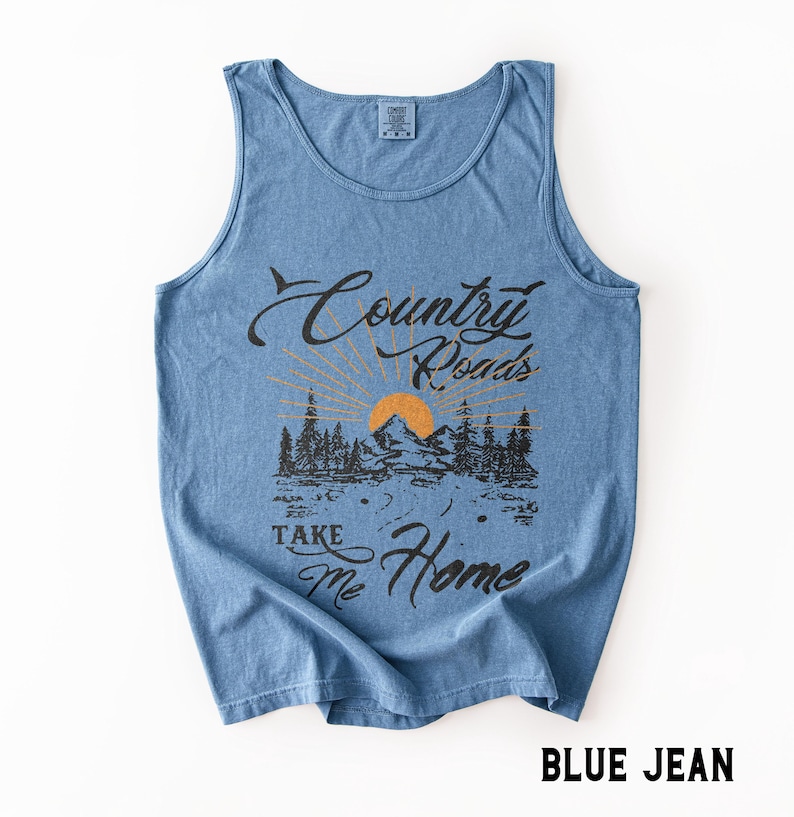 K&ouml;nnte beinhalten: Hellblaues Tanktop mit dem Text "Country Roads Take Me Home". Das Design zeigt eine Berglandschaft mit Sonne und B&auml;umen. Das Tanktop hat die Farbe Blue Jean.