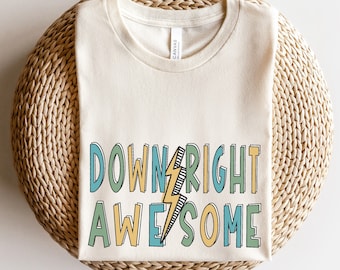 May include: A natural colored t-shirt with the text "DOWNRIGHT AWESOME" in colorful block letters with a lightning bolt graphic.