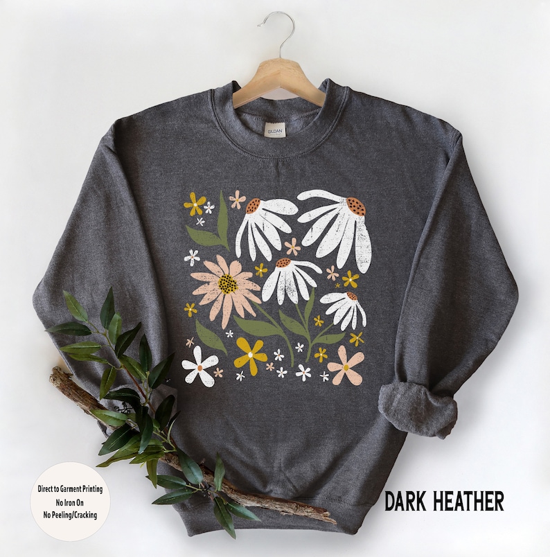 K&ouml;nnte beinhalten: Dunkelgrauer Sweatshirt mit einem Blumendruck mit wei&szlig;en, rosa und gelben Blumen. Der Text "Direct to Garment Printing No Iron On No Peeling/Cracking" und "DARK HEATHER" ist auf dem Sweatshirt aufgedruckt.