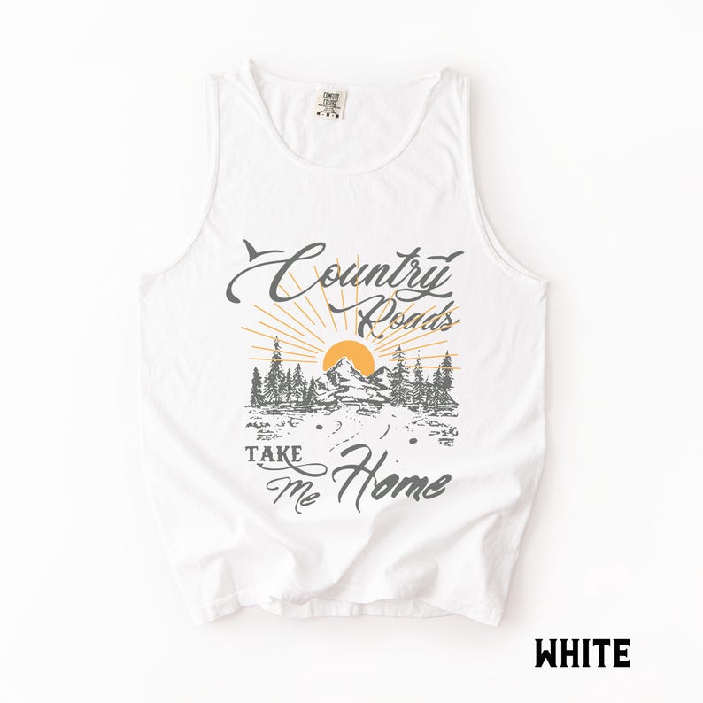 K&ouml;nnte beinhalten: Wei&szlig;es Tanktop mit dem Text "Country Roads Take Me Home" in grauer Schrift. Die Grafik zeigt eine Berglandschaft mit Sonne und B&auml;umen. Das Wort "WHITE" ist unten rechts aufgedruckt.