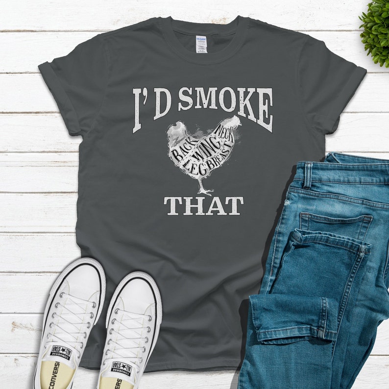 May include: A dark gray t-shirt with a white graphic of a chicken with the words "I'd Smoke That" printed below. The chicken is labeled with different parts of the bird, such as "back", "wing", "leg", and "breast".