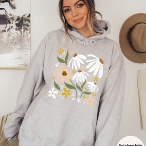 K&ouml;nnte beinhalten: Ein grauer Kapuzenpullover mit einem Blumendruck mit wei&szlig;en G&auml;nsebl&uuml;mchen, rosa und gelben Blumen und gr&uuml;nen Bl&auml;ttern. Der Text "SPORT GREY" ist oben im Bild in Schwarz gedruckt. Der Text "Direct to Garment Printing No Iron On No Peeling/Cracking" ist unten im Bild gedruckt.