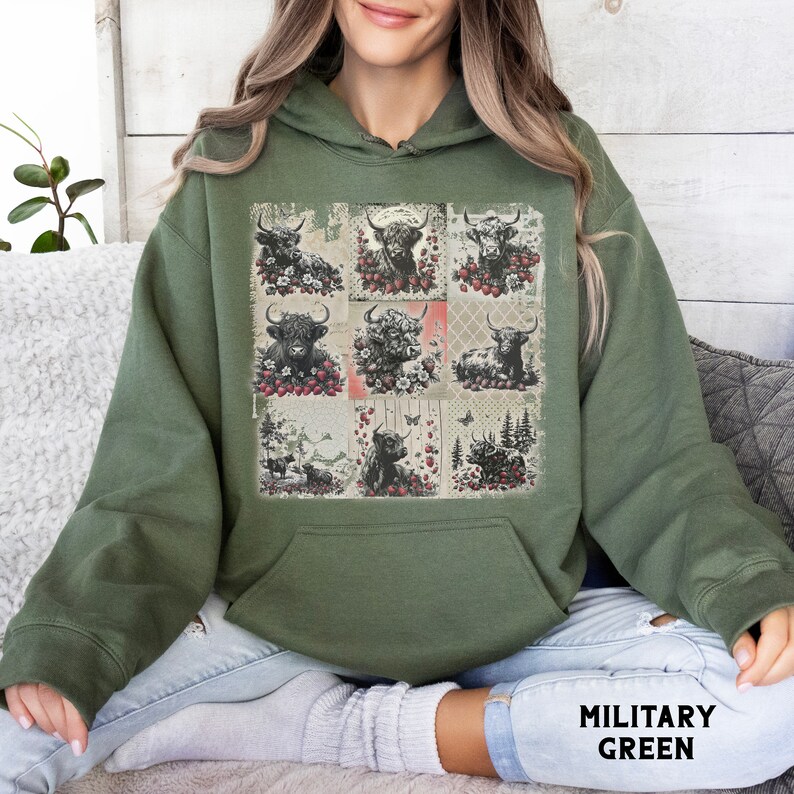 May include: A green hooded sweatshirt with a patchwork design featuring a collage of highland cows, flowers, and butterflies. The sweatshirt has a large pocket on the front.