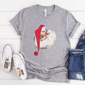 May include: A gray t-shirt with a vintage illustration of Santa Claus with a red hat and white beard.