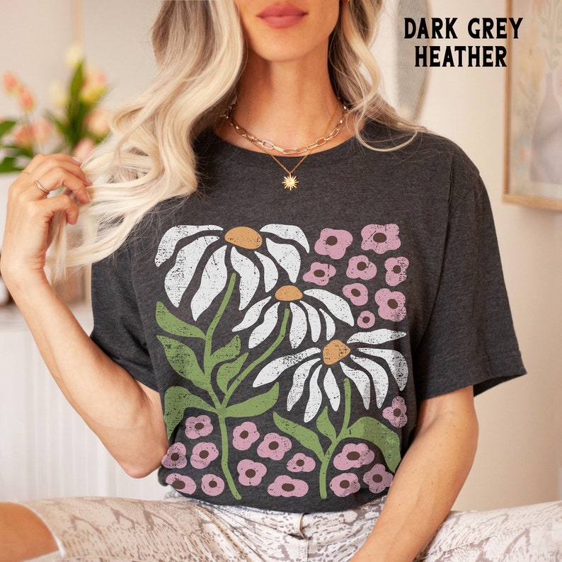 K&ouml;nnte beinhalten: Dunkelgraues T-Shirt aus Heather-Material mit einem grafischen Druck von wei&szlig;en G&auml;nsebl&uuml;mchen und rosa Blumen.