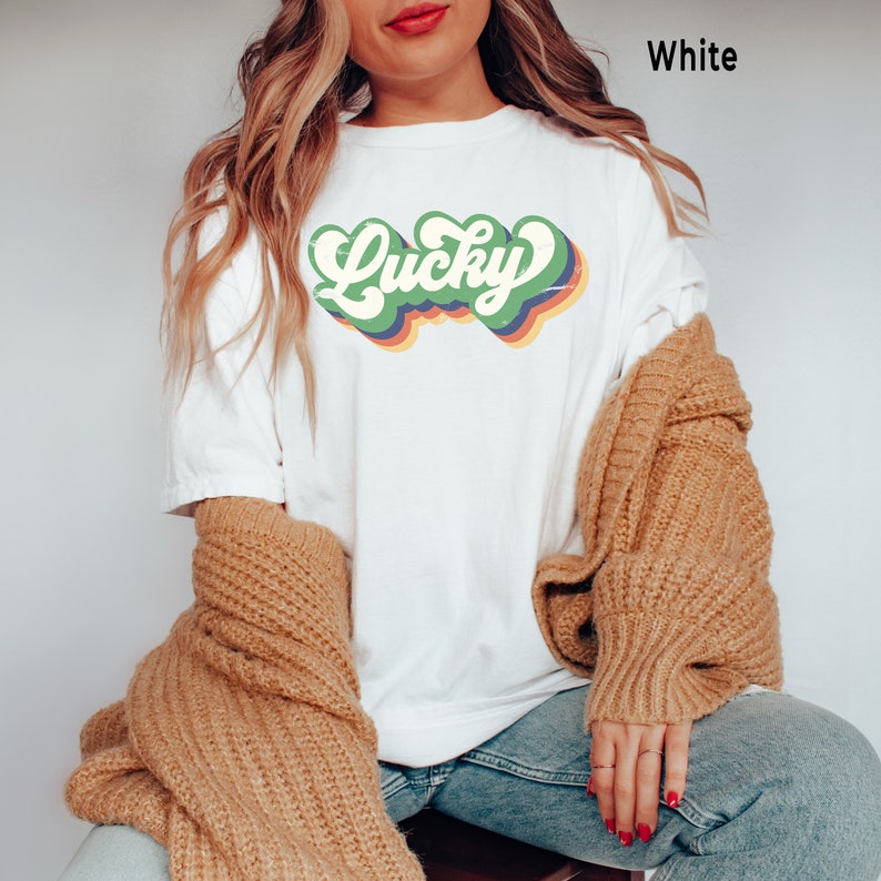 May include: A white t-shirt with a retro green, yellow, orange, and blue "Lucky" graphic.