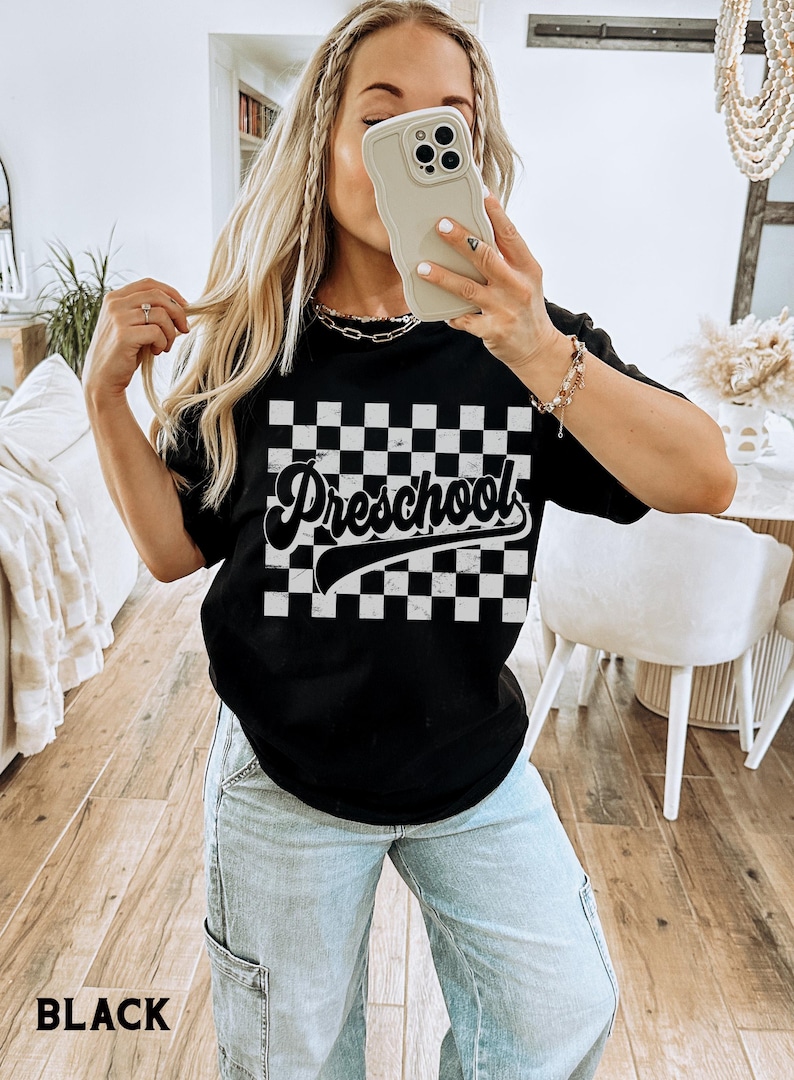 Pu&ograve; includere: T-shirt nera con motivo a scacchi e la scritta "Preschool" in corsivo. La maglietta &egrave; a girocollo. La parola "BLACK" &egrave; stampata in basso nell'immagine.