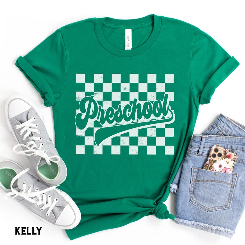 Pu&ograve; includere: Una maglietta verde con la scritta "Preschool" in bianco, con un font retr&ograve;, su uno sfondo a scacchi. La maglietta &egrave; abbinata a scarpe da ginnastica grigie e pantaloncini di jeans. La parola "KELLY" &egrave; stampata in basso.