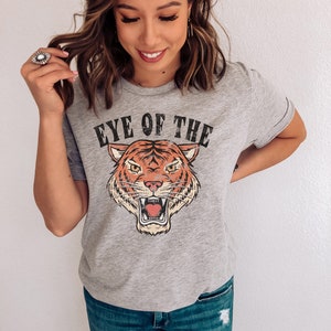 May include: Gray t-shirt with a vintage-style tiger graphic and the text "Eye of the Tiger".