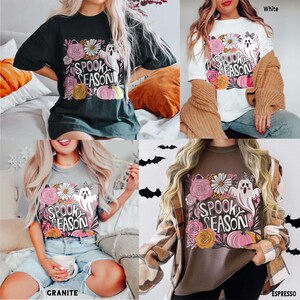 May include: Four t-shirts in black, white, granite, and espresso colors. Each shirt features a floral and ghost graphic with the text "Spook Season". The design includes pink pumpkins and flowers.