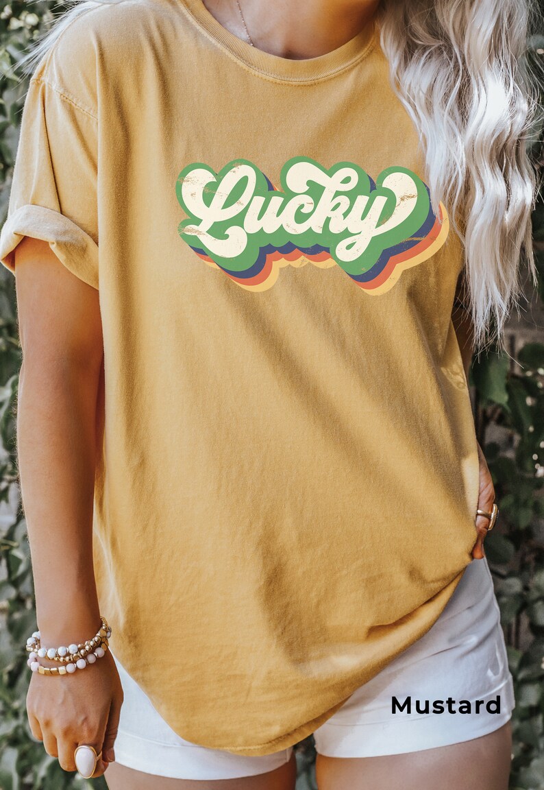 May include: A mustard yellow t-shirt with a retro-style graphic that says "Lucky" in green, red, blue, and orange.