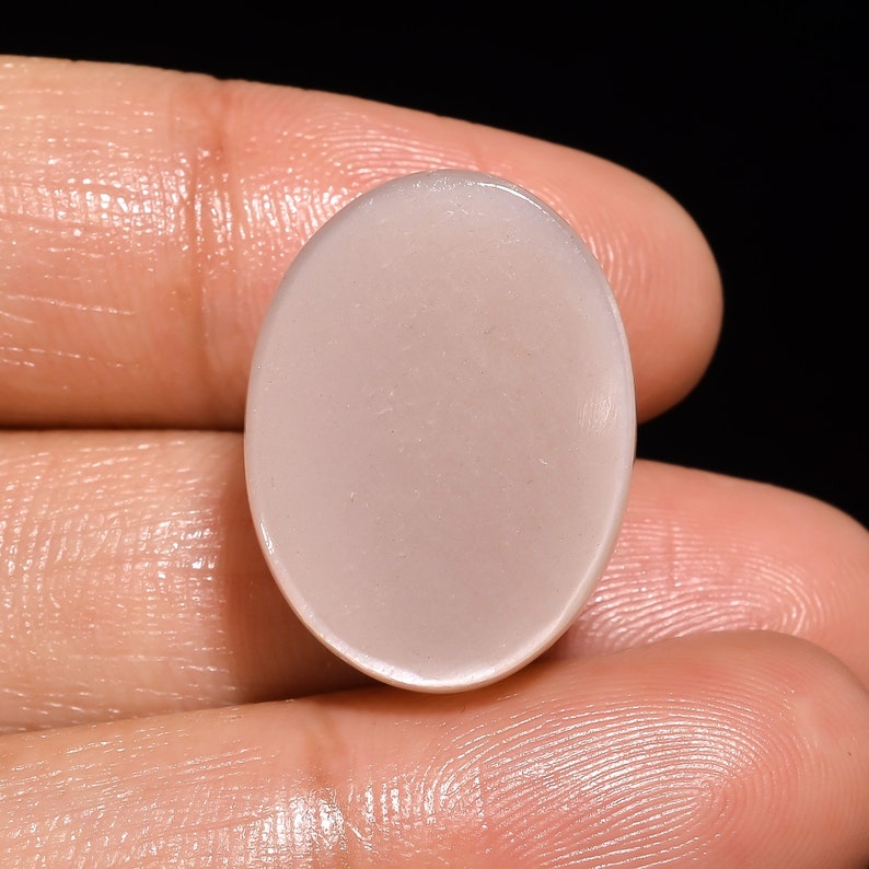 May include: A smooth, oval-shaped, light pink gemstone cabochon.