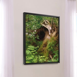 May include: A framed painting of a forest scene with a large tree trunk with a hollow in the center. The tree is surrounded by lush green foliage and ferns.