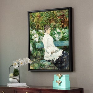 May include: A dark wood console table with three drawers and gold hardware. The table has a white stool and a stack of two teal blue boxes with gold accents. A framed painting of a woman sitting on a bench in a garden hangs on the wall above the table.