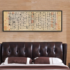 May include: A brown leather headboard with button tufting and wingback design. The headboard is against a wood-paneled wall with a framed piece of calligraphy art hanging above it.