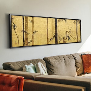 May include: A black framed painting with a gold background and black ink illustrations of bamboo stalks and a monkey. The painting is hanging on a wall above a brown couch.