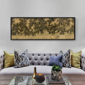 May include: A black framed print of a traditional Japanese painting depicting a dragon in a swirling cloud formation. The print is hanging above a gray tufted sofa with pillows in various patterns and colors.
