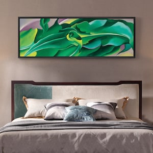 Puede incluir: Una pintura abstracta enmarcada de hojas verdes con un fondo morado claro. La pintura está colgada en una pared sobre una cama con una cabecera marrón y almohadas blancas y verdes.