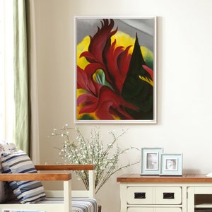 May include: A framed abstract painting of red and yellow flowers with a black background. The painting is in a white frame and is hanging on a white wall.