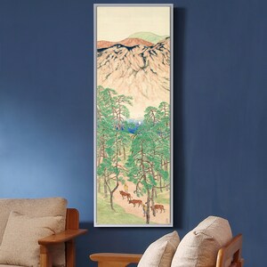 May include: A framed painting depicting a mountain landscape with a group of people and animals walking through a forest. The painting is done in a traditional Japanese style with muted colors and delicate brushstrokes.