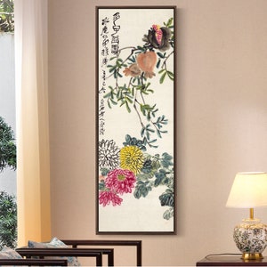 May include: A vertical painting of a pomegranate branch with red, yellow, and white flowers. The painting is framed in a brown wood frame. The painting has Chinese calligraphy in black ink.
