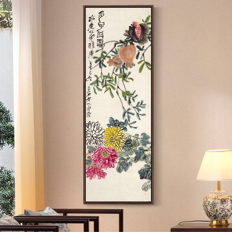 May include: A vertical painting of a pomegranate branch with red, yellow, and white flowers. The painting is framed in a brown wood frame. The painting has Chinese calligraphy in black ink.