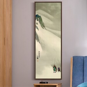 May include: A framed print of a Japanese landscape painting depicting a snowy mountain scene with two figures in the foreground. The painting is in shades of gray, white, and green, with a subtle brushstroke texture. The text "雪中行" is written in black ink on the right side of the painting.