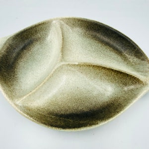 Puede incluir: Un plato para servir de cerámica blanco y marrón con tres secciones. El plato tiene forma de hoja y tiene un esmalte moteado.